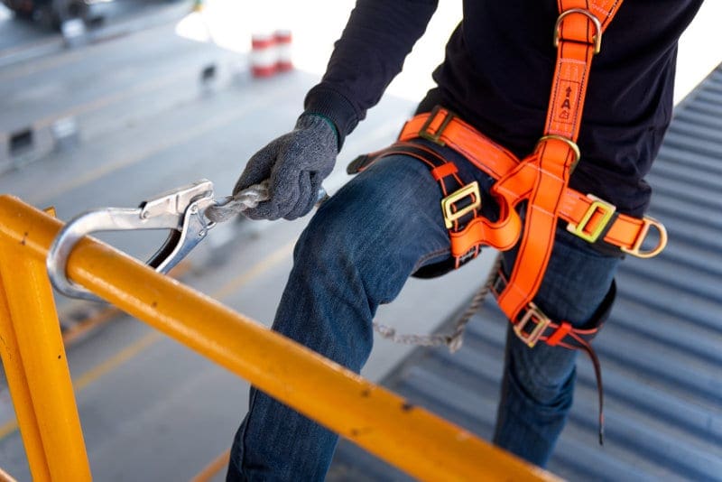 Roofer roof construction worker wearing safety harness